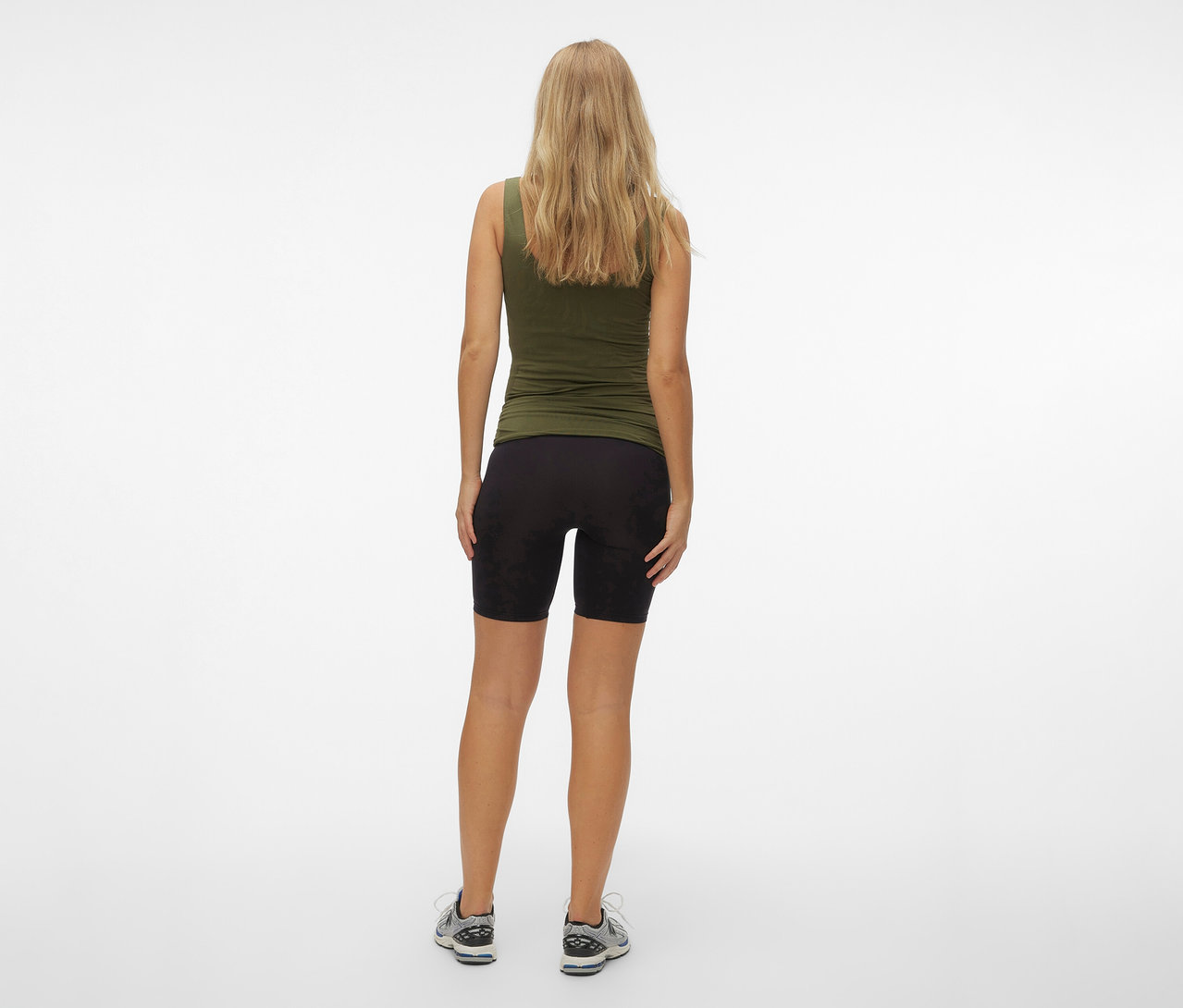 Hátulnézet egy olívazöld trikót és fekete MAMALICIOUS kismama rövidnadrágot viselő nőről.