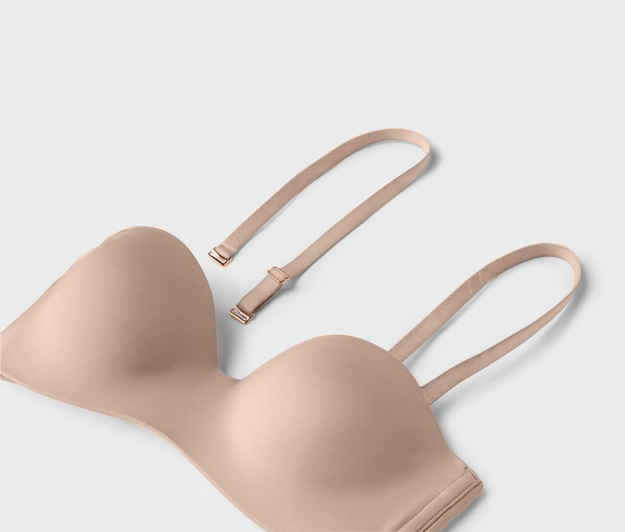 Egy testszínű, pánt nélküli melltartó levehető pántokkal világos háttérrel.