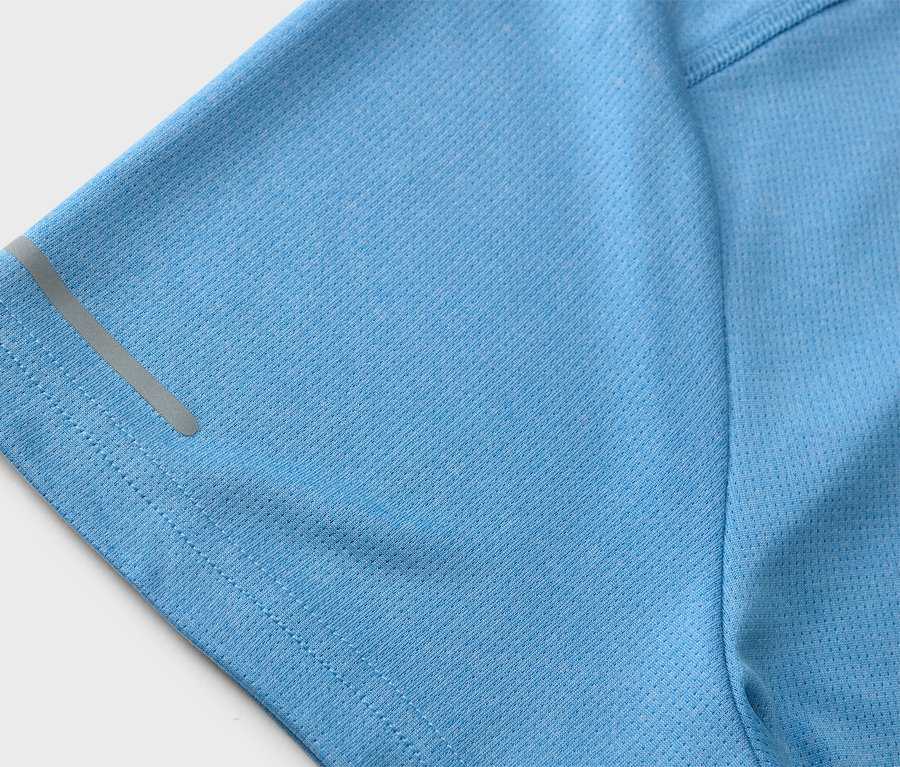 Egy világoskék sportpóló részletfotója, fényvisszaverő csíkkal az ujján.