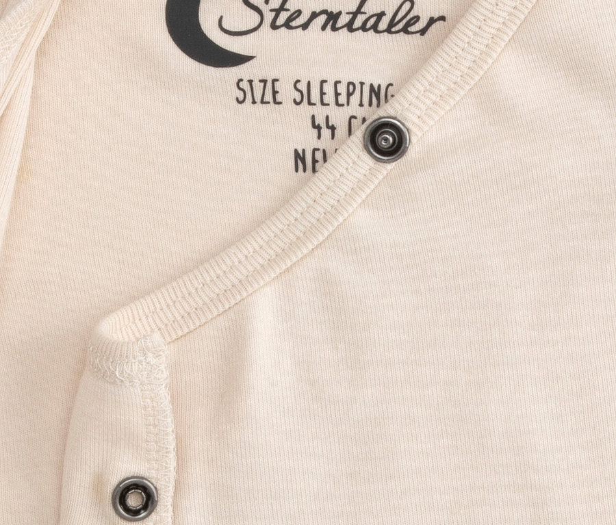 Krém színű Sterntaler bébi belső hálózsák közelképe, patentokkal és részben látható „SIZE SLEEPING” felirattal.