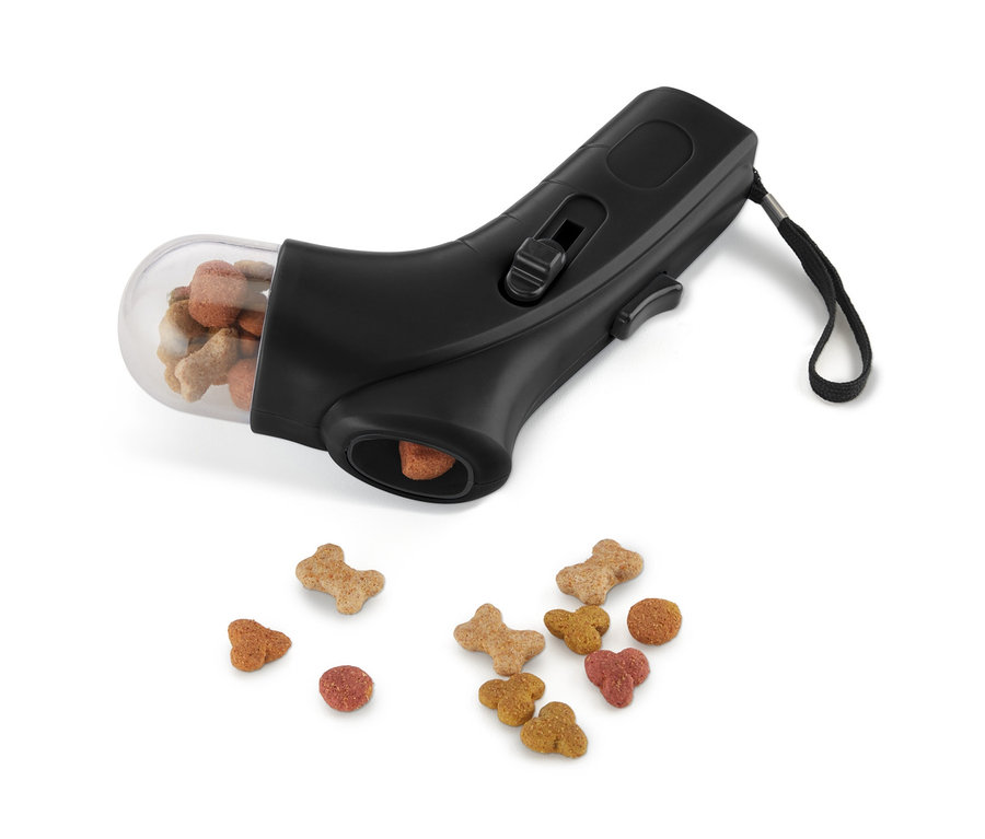 Fekete jutalomfalat adagoló tele tartállyal és alatta szétszórt jutalomfalatokkal.