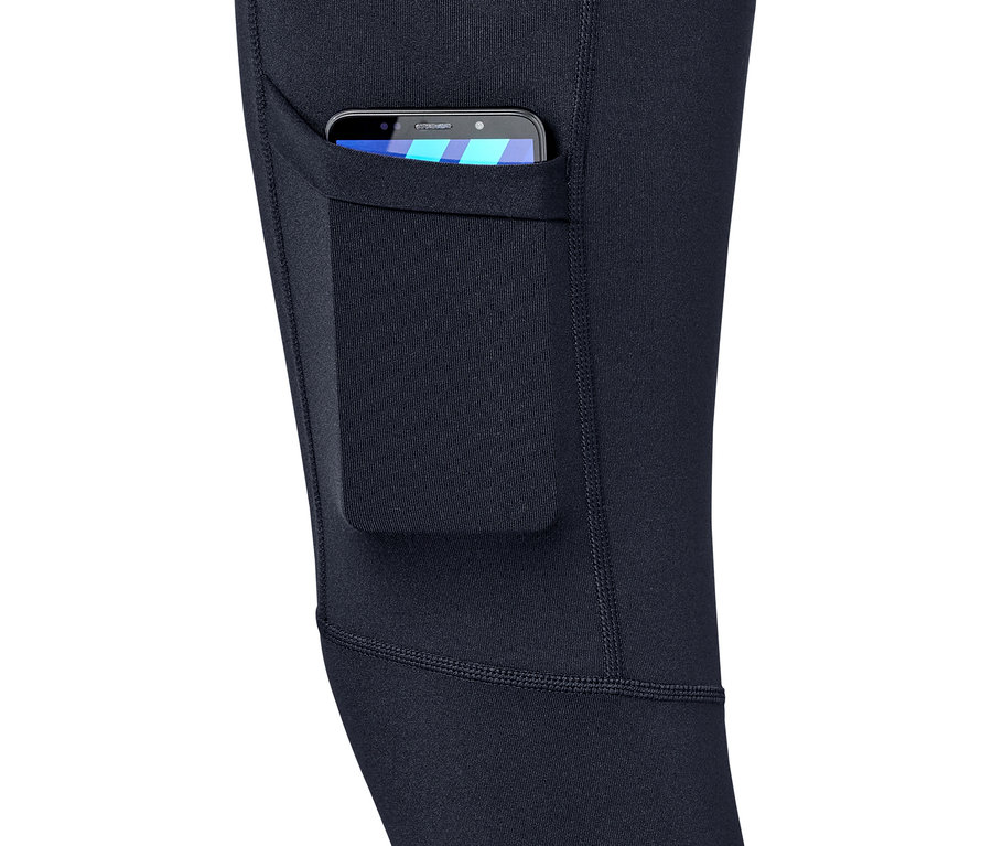 Egy sötétkék női funkcionális túranadrág részlete, zsebbel, amiben egy mobiltelefon van.