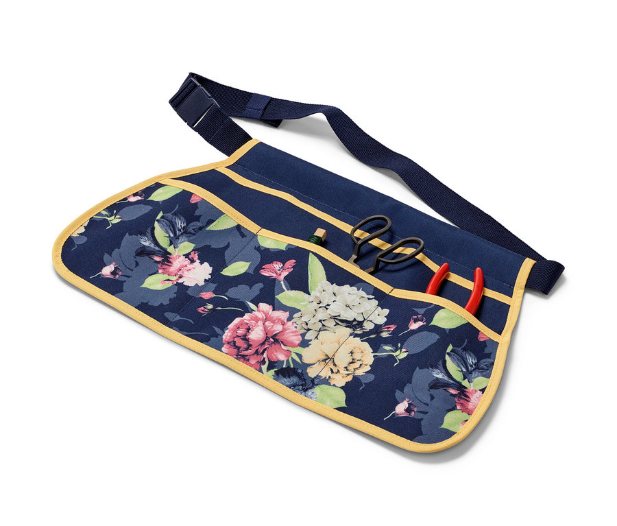 Virágos kerti szerszámtartó öv szerszámokkal a zsebekben.