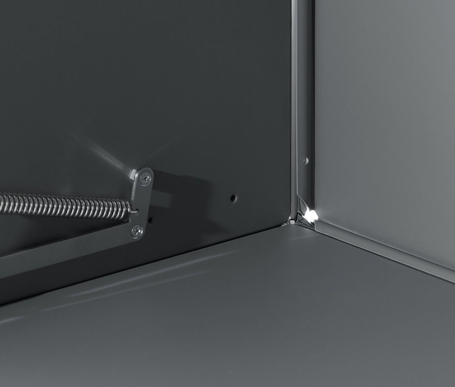 A szürke »CN3« komód részlete, lenyitható ajtóval és fém mechanizmussal.