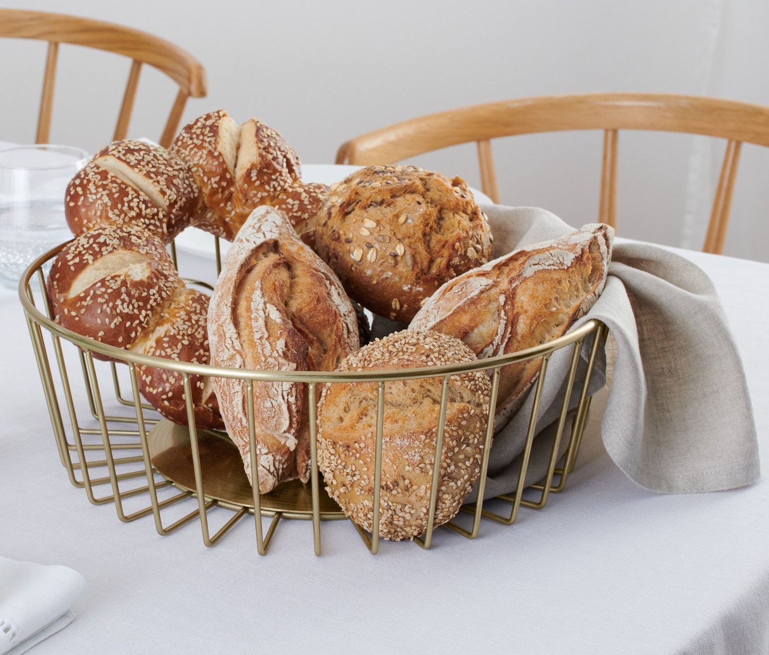 Egy asztalon egy drótkosár, pezsgőarany színben, kenyérrel.