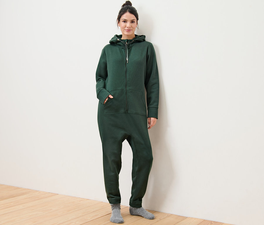 Nő pózol sötétzöld női kezeslábasban.