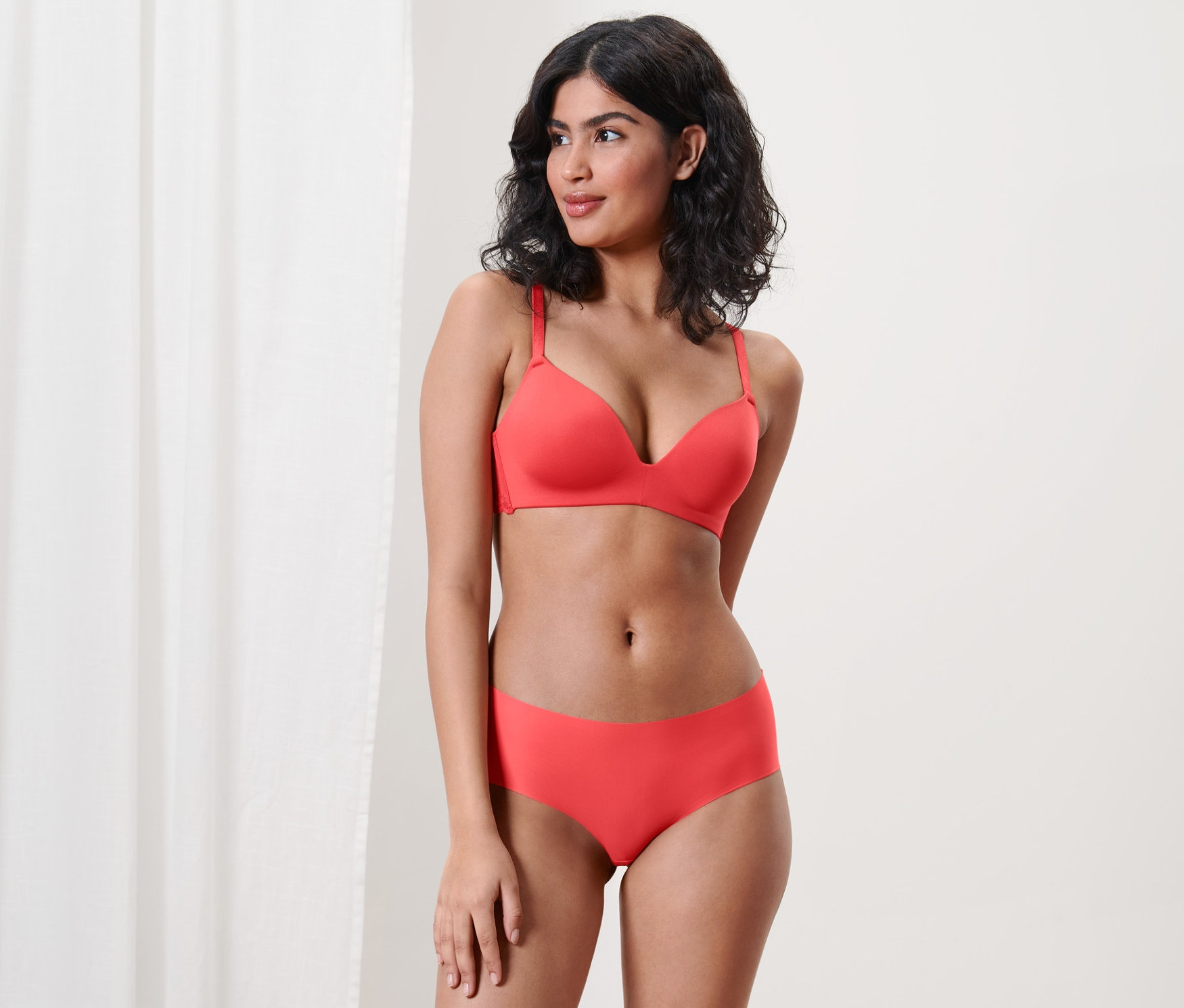 Nő pózol piros melltartóban és 2 darabos Magic Cut alsóban.