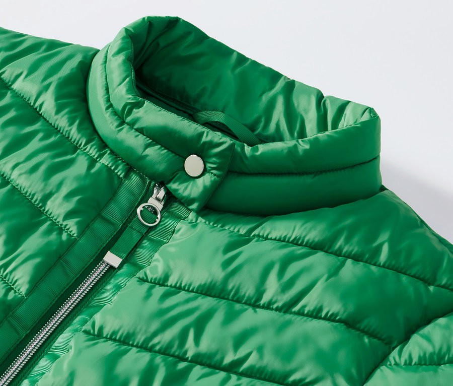 Egy zöld, női steppelt dzseki részlete.