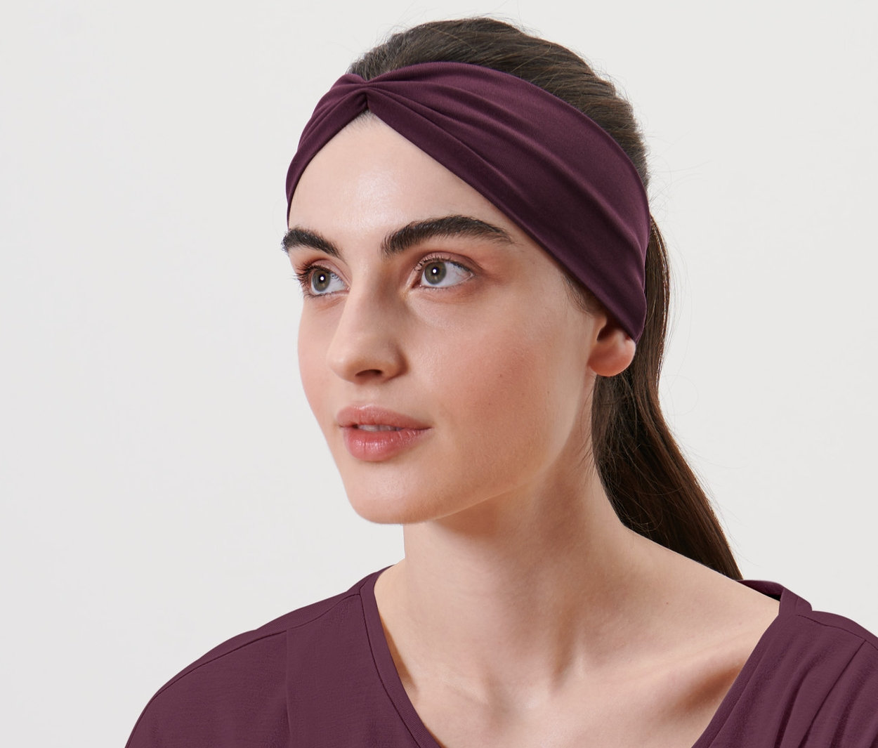 Nő visel egy padlizsán színű női funkcionális fejpántot.