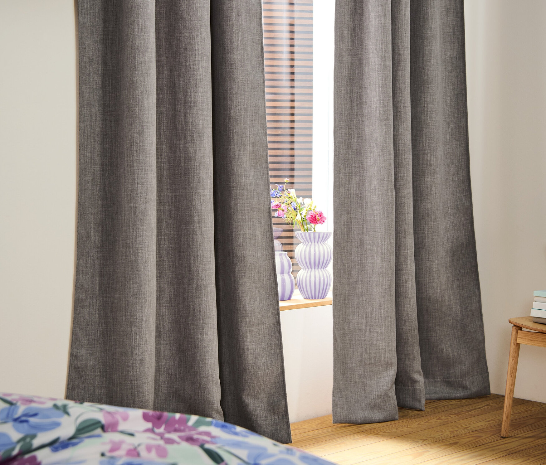 Két sötétítőfüggöny egy ablak előtt. Az ablakban redőnyök vannak.