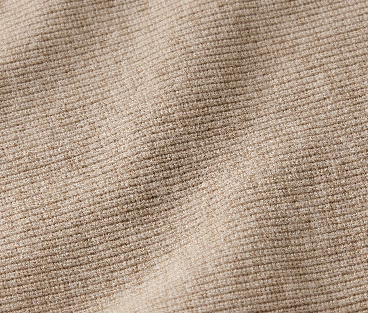 Közeli kép egy bézs színű bordázott anyagról.