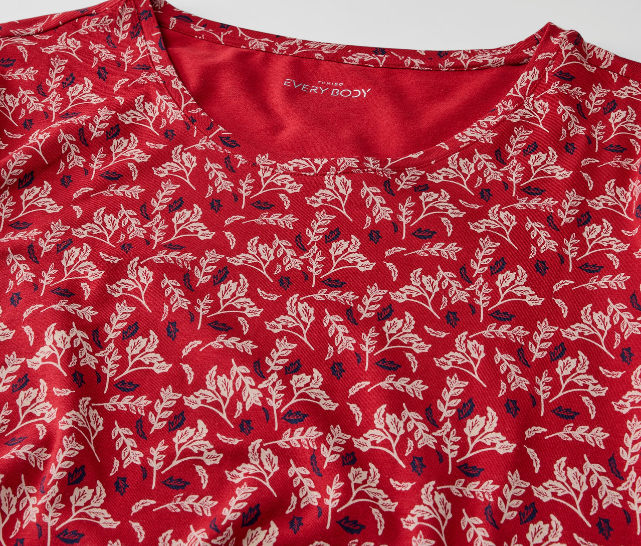 Egy piros, leveles mintás póló részlete.