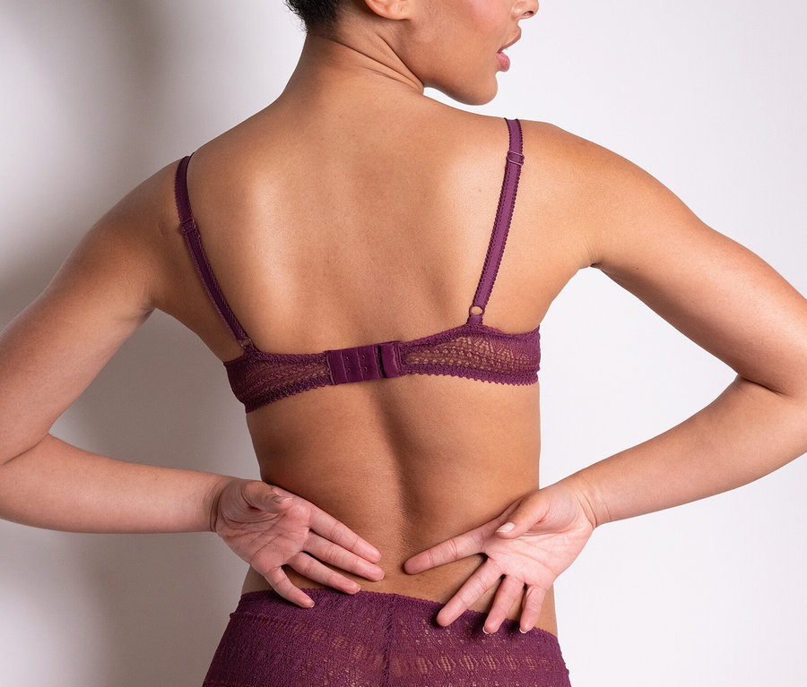 A nő háttal a kamerának, lila Passionata merevítős melltartót »Leila« és hozzáillő alsót visel.