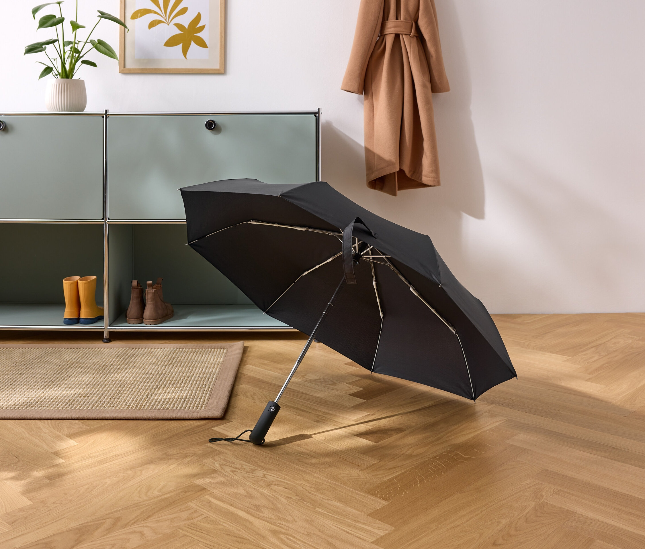 Egy fekete esernyő fekszik a parkettás padlón egy folyosón.