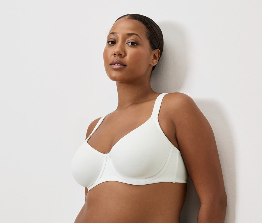 Portré egy barna bőrű nőről fehér melltartóban.