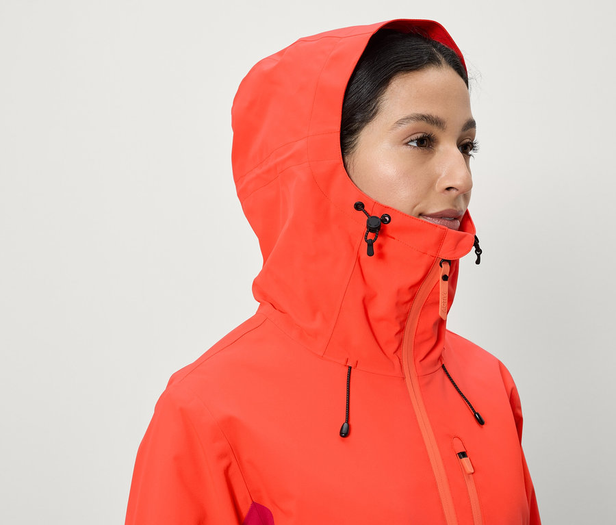 Egy nő korallpiros kapucnis kabátot visel.