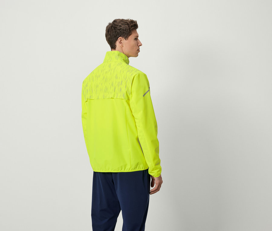 Egy férfi neon sárga futódzsekiben és sötétkék nadrágban áll háttal a kamerának.