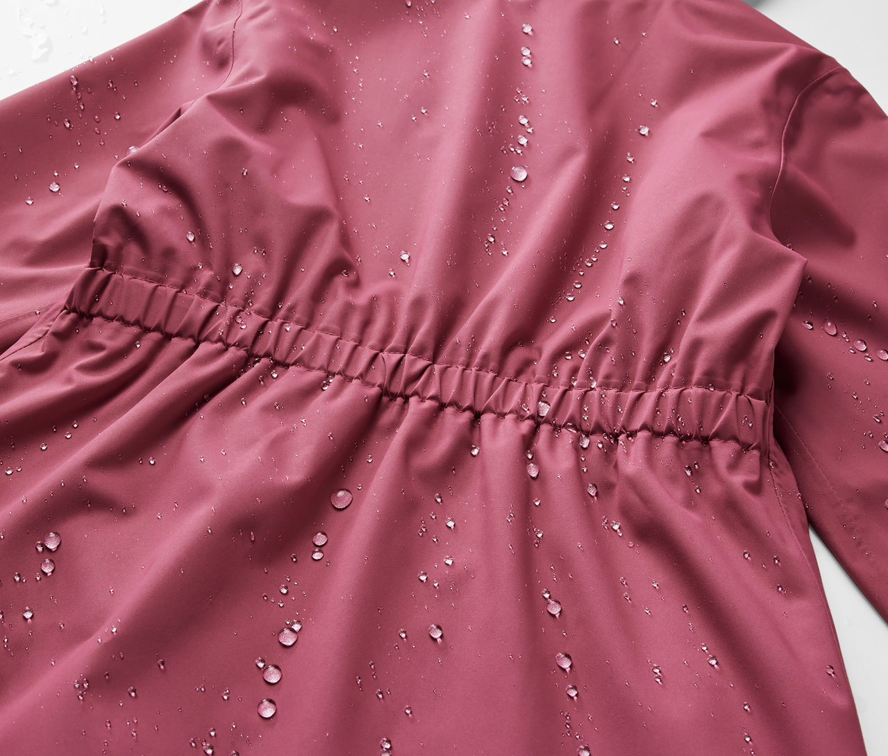 Közeli kép egy gyermek esőkabát hátuljáról vízcseppekkel.