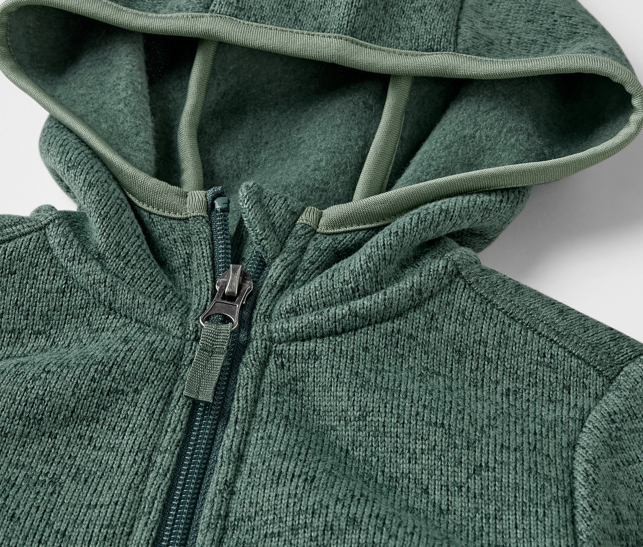 Egy kötött polárfelső részlete, cipzárral és kapucnival.