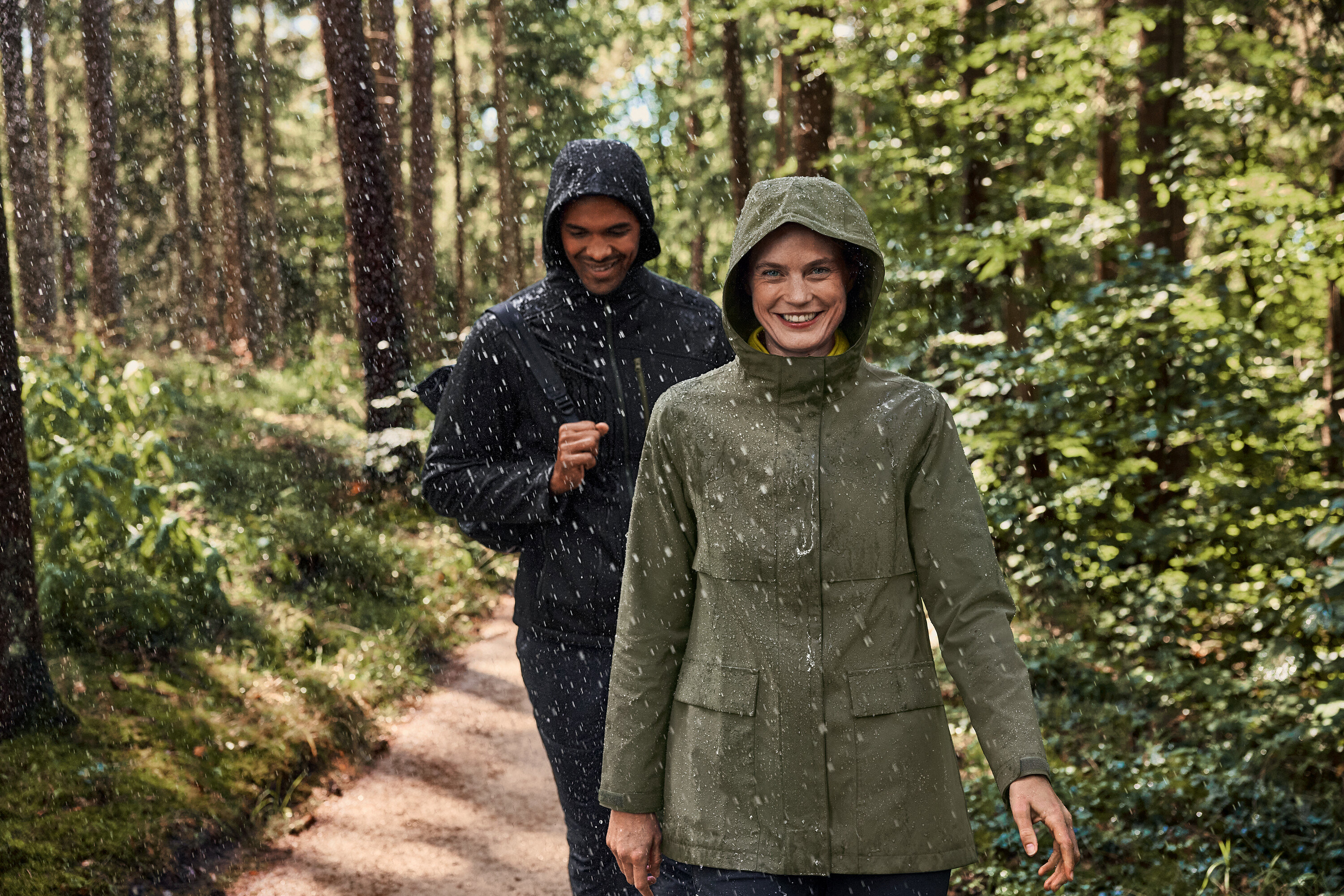 Két ember sétál az esőben az erdőben. A nő khaki-antracit színű polárpulóvert visel.