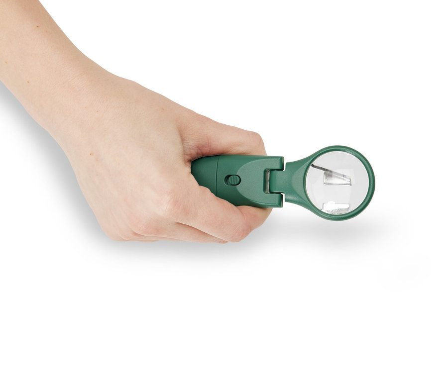 Egy kéz egy LED-es kullancskiszedő csipeszt tart.