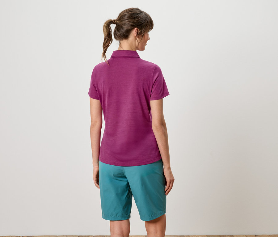 Hátulnézet egy lófarokba kötött hajú nőről, aki lila pólót és türkiz rövidnadrágot visel.
