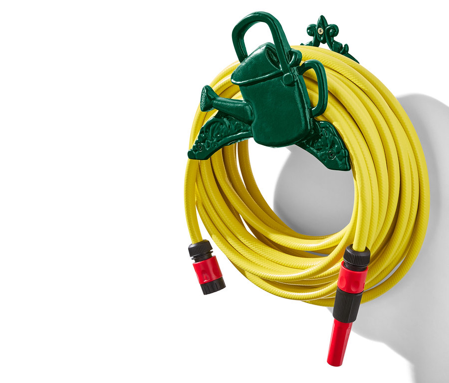 Sárga kerti tömlő feltekercselve egy sötétzöld, locsolókanna alakú tartóra.