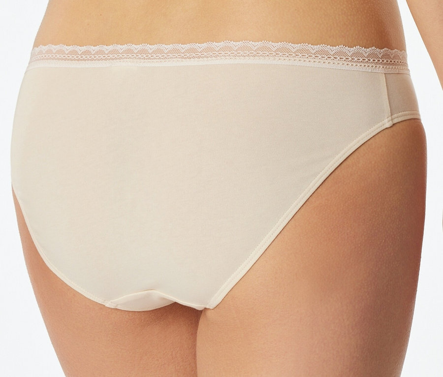 Egy nő hátulnézetének közeli képe, aki testszínű, csipkés szegélyű alsónadrágot visel.