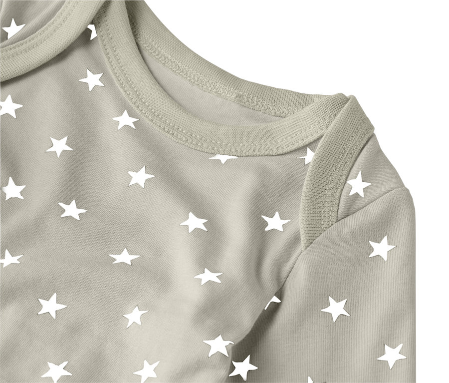 Közeli kép egy világosbarna, fehér csillagokkal díszített baba bodyról.