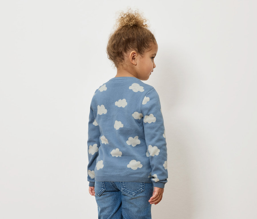 Hátulról látható gyermek, felhőmintás kék pulóvert és farmert visel.