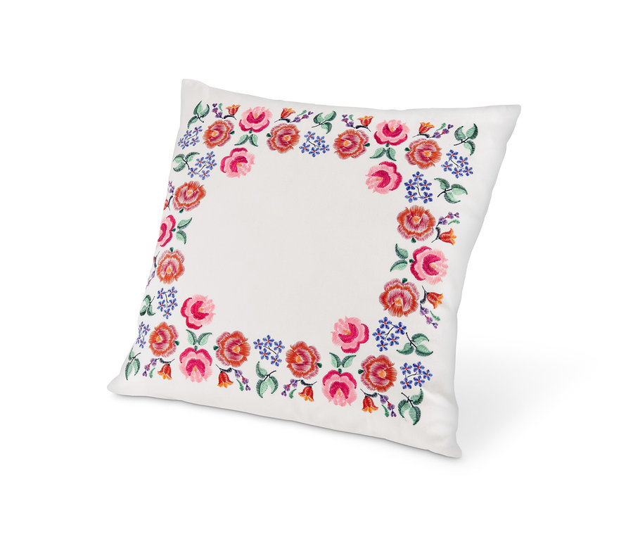 Virágos hímzéssel díszített, töltött fehér díszpárna.