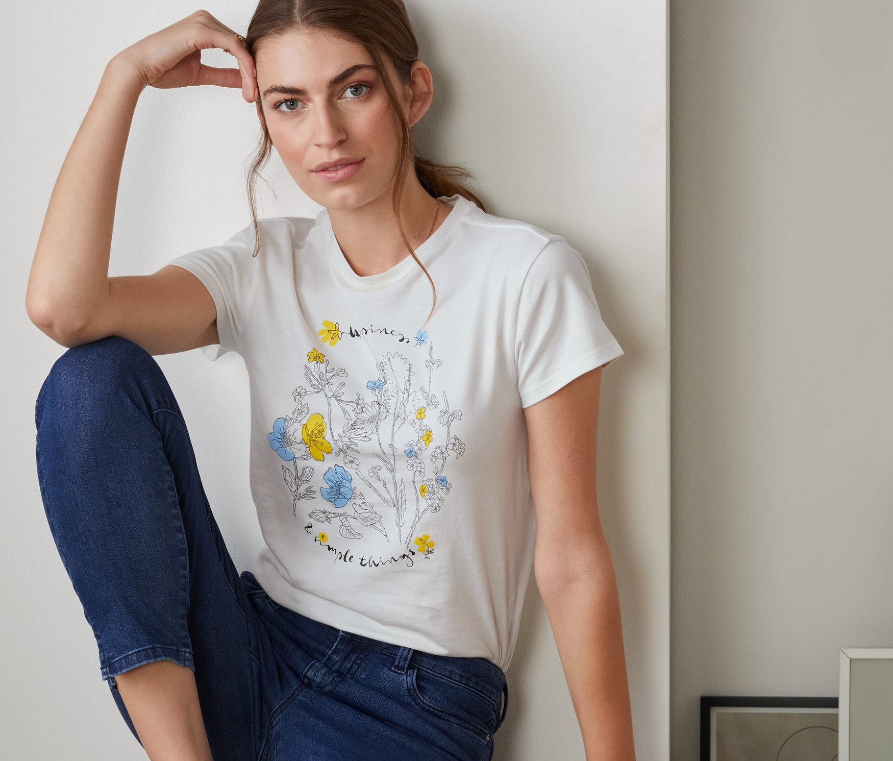 Nő ül és virágos női pólót visel.