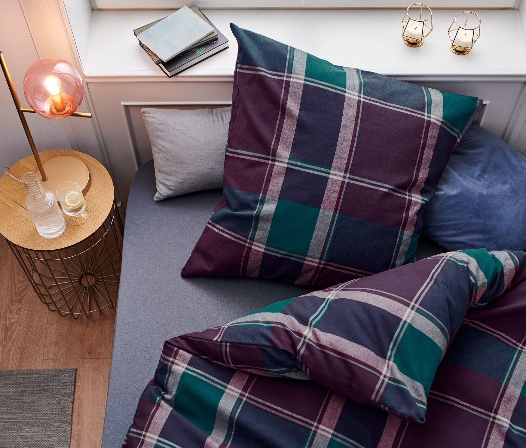 Felülnézet egy ágyról, kockás, lila és zöld színű flanel ágyneművel.