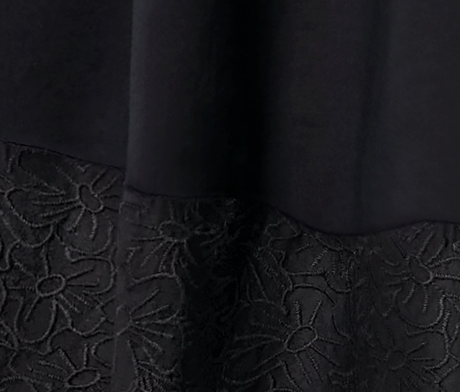 Egy fekete, hímzett szövött ruha részlete.