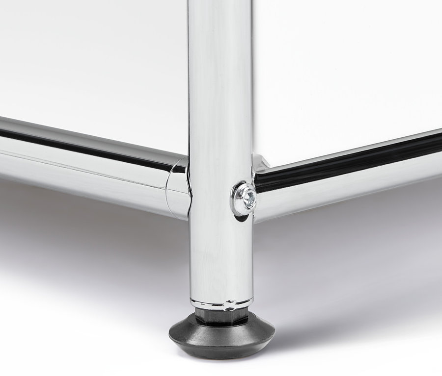 A »CN3« polcos komód sarkának részlete lenyitható ajtóval, krómozott láb fekete talppal.