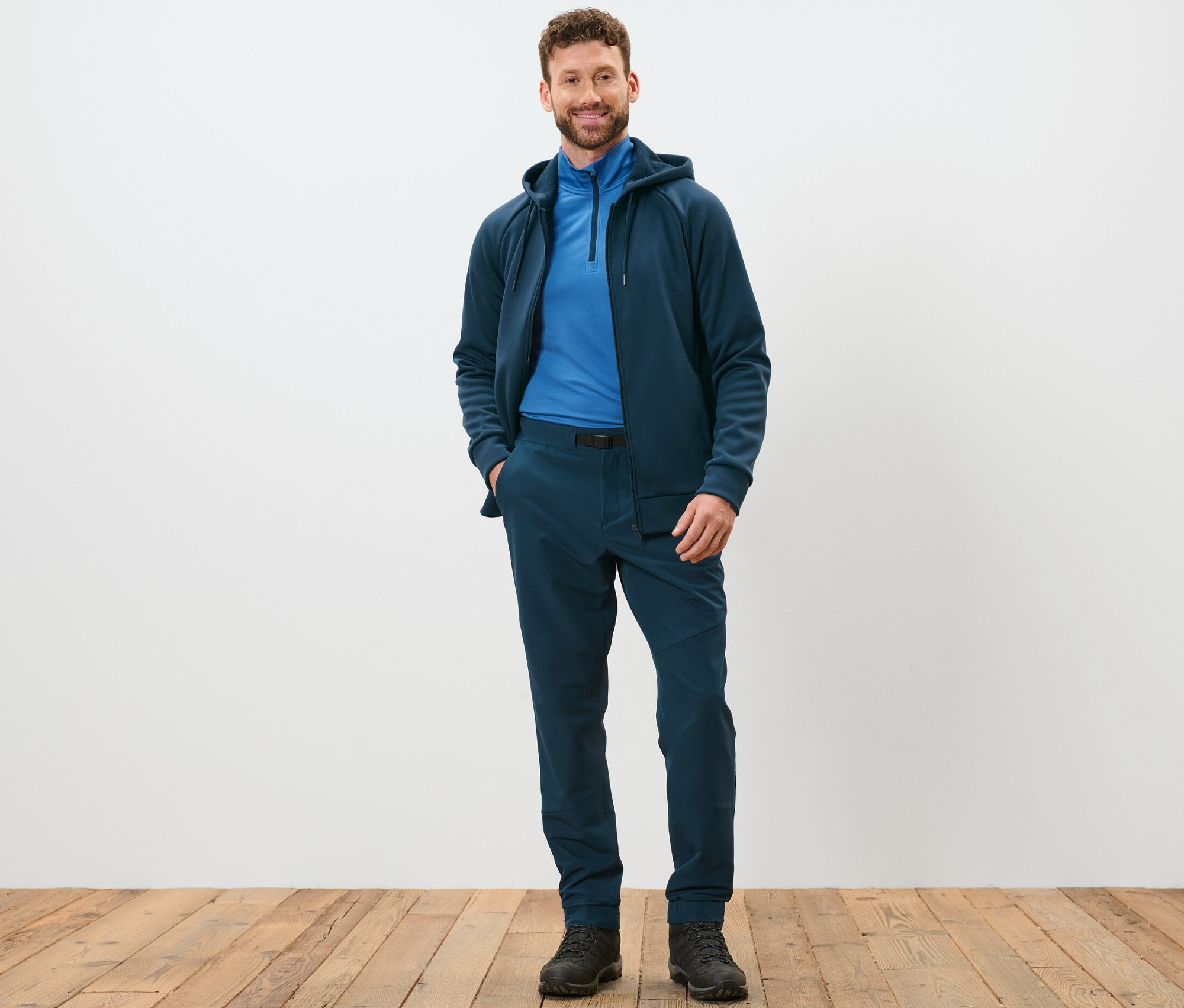 Egy férfi áll és pózol sötétkék termonadrágban.