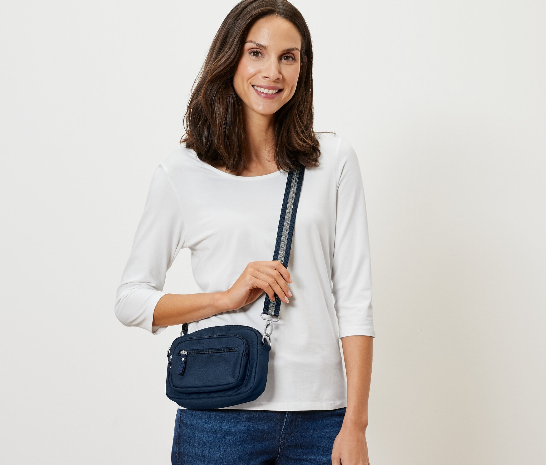 Nő pózol egy sötétkék biztonsági oldal- és övtáskával.