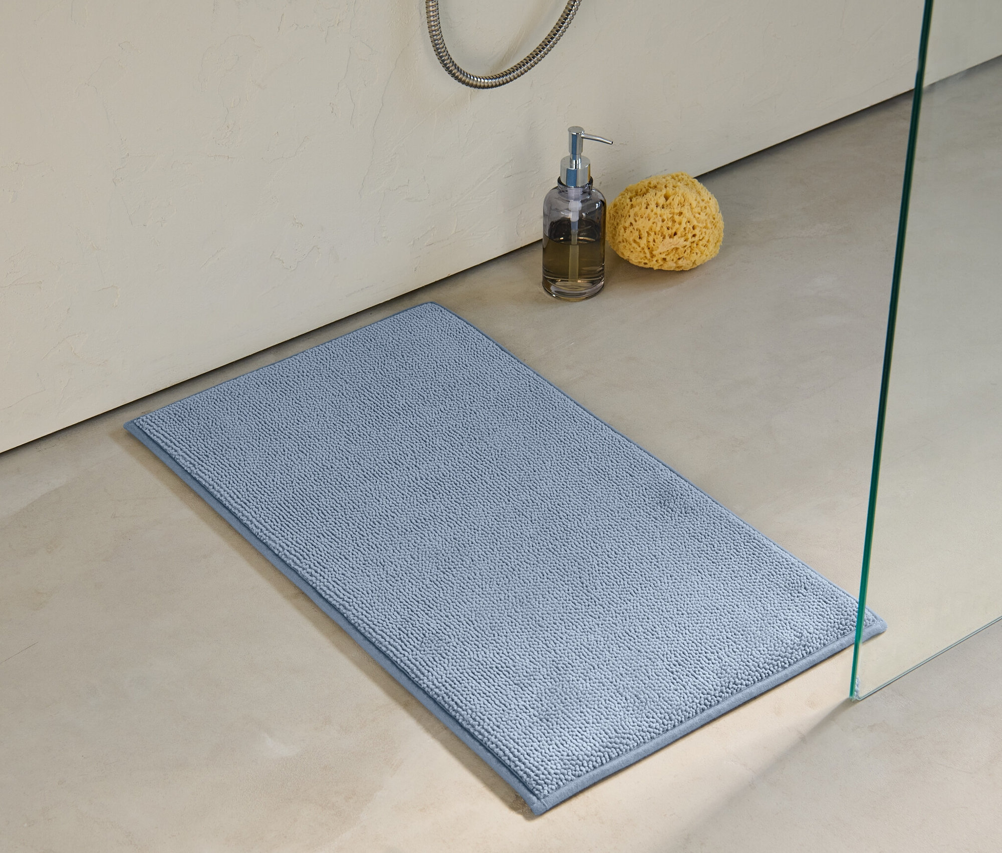 Világoskék memóriahabos kádkilépő, 40 x 70 cm-es méretben a padlón, a zuhanyzó mellett.