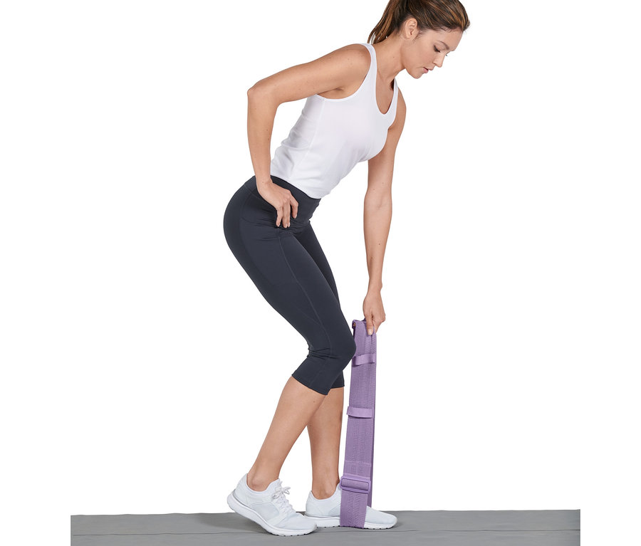 Nő edz egy állítható fitneszszalaggal, egyik lábával rálépve.