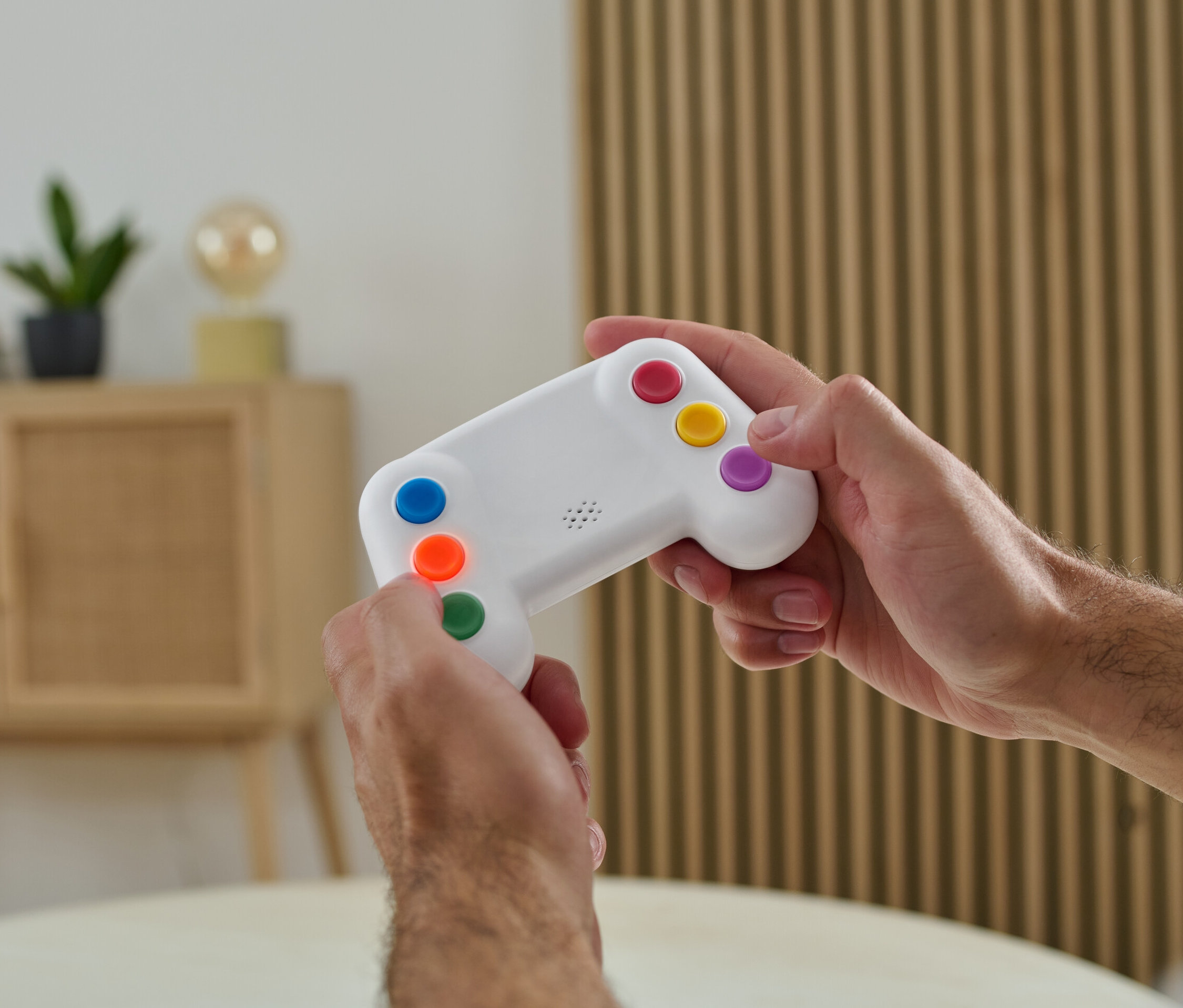 Egy férfi színes gombokkal ellátott elektronikus memóriajátékot tart a kezében.