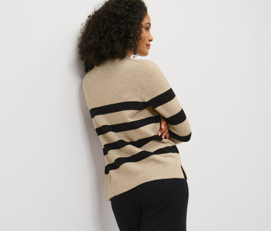 Nő pózol csíkos kötött pulóverben.