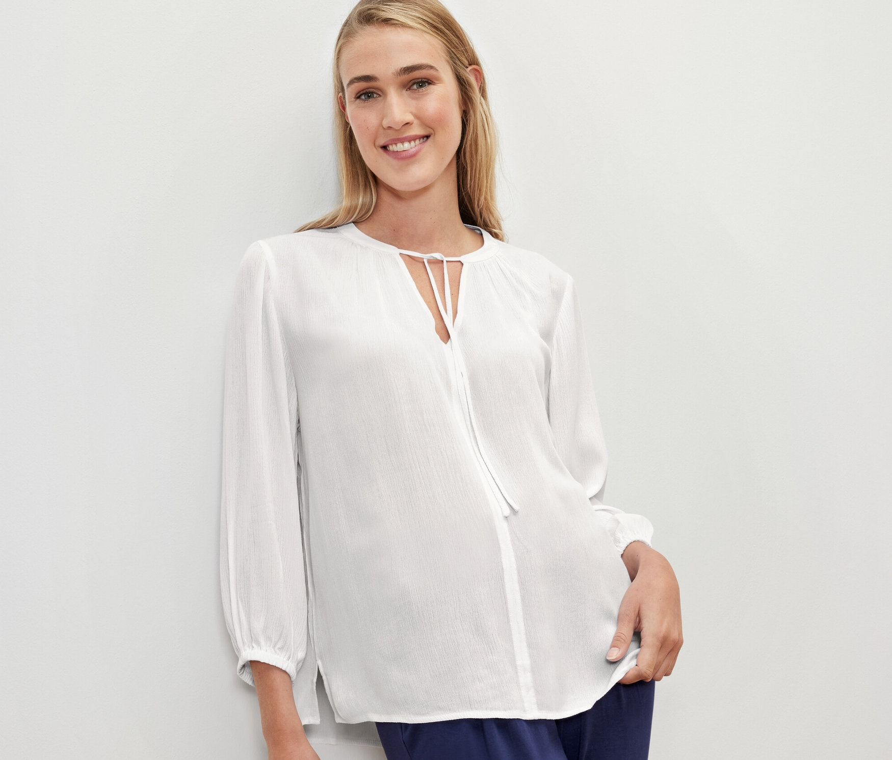 Nő visel egy fehér női 7/8-os ujjú tunikablúzt.