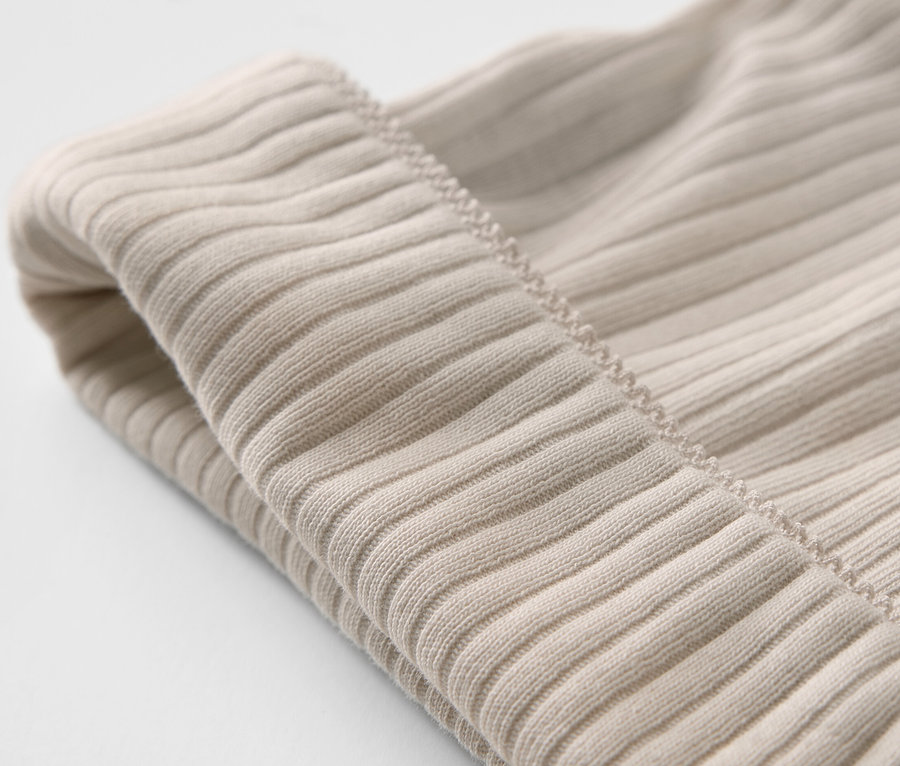 Két világos bézs színű kisgyerek sapka közelről.