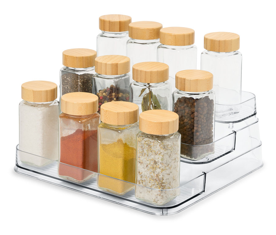 Egy átlátszó, háromszintes szervezőn 12 üveg fűszertartó található fa fedőkkel.