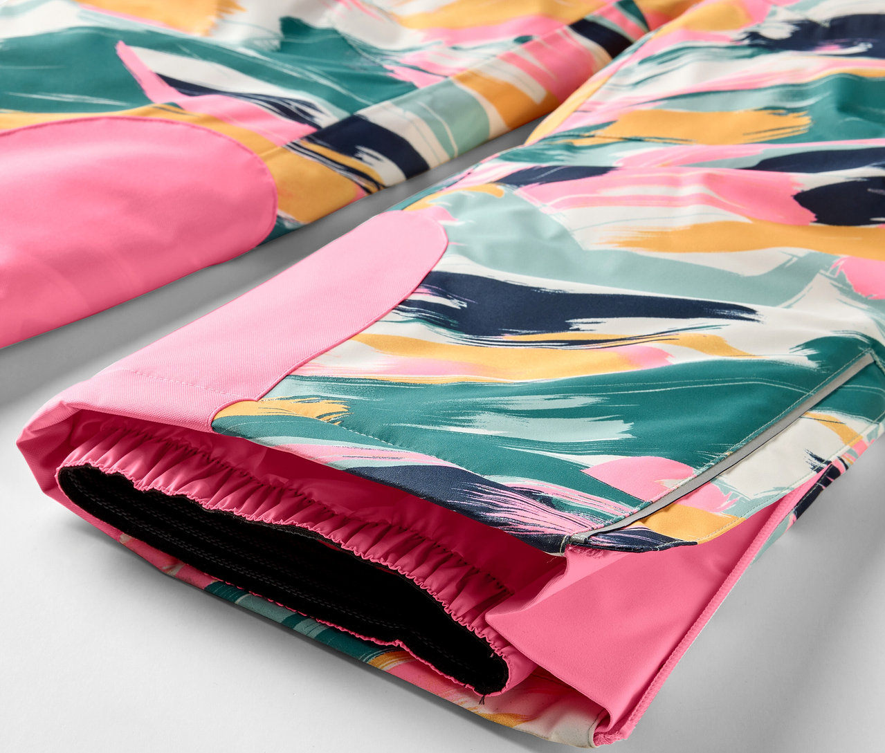 Egy színes nadrág részlete rózsaszín részletekkel.