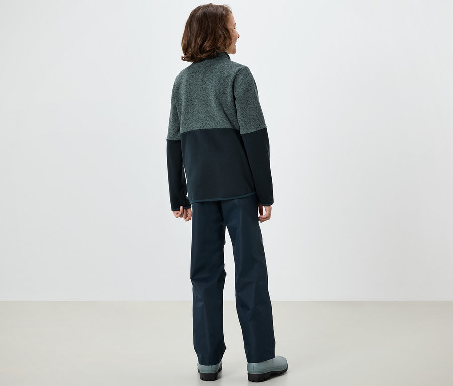 Egy fiú háttal áll a kamerának, és Kinder-Hybrid-Strickfleecejacke-t visel.