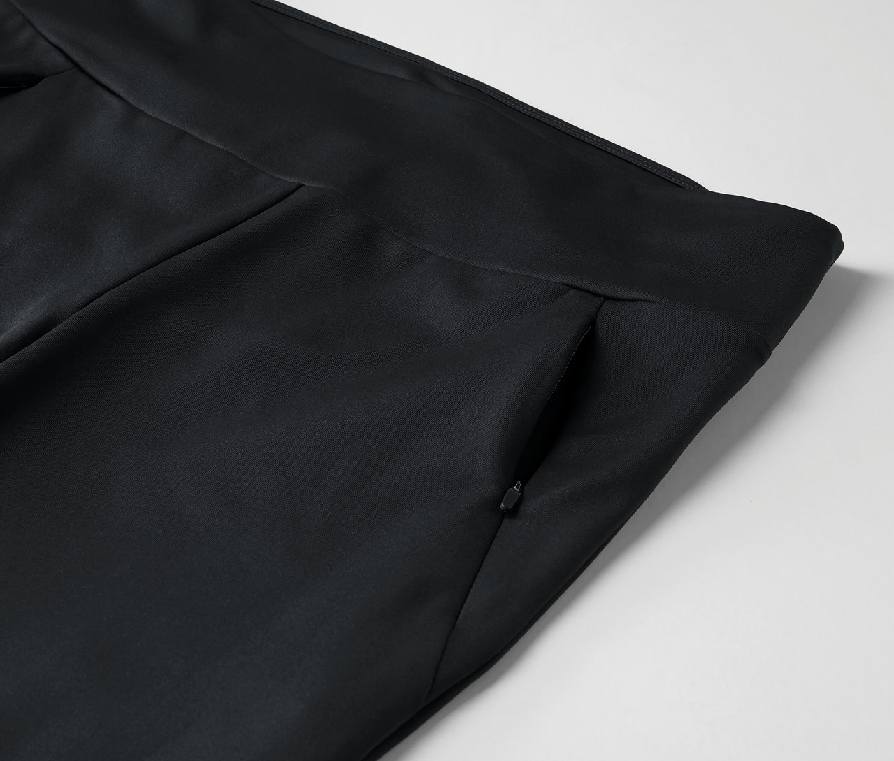Egy fekete nadrág részlete cipzáras zsebbel.