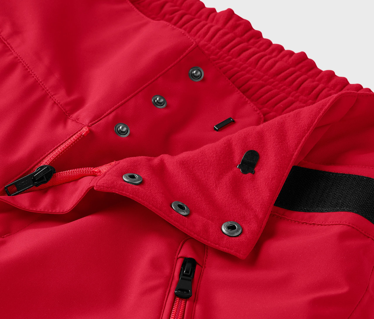 Egy piros nadrág részlete cipzárral és patentokkal.