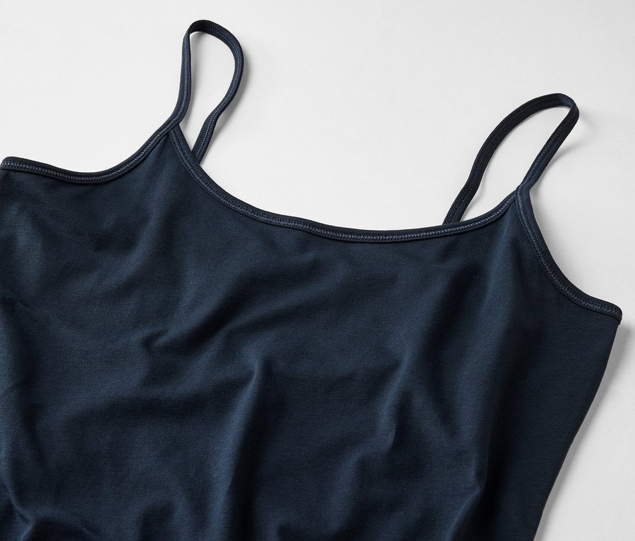 Közeli kép egy sötétkék női trikóról vékony pántokkal, világos háttérrel.