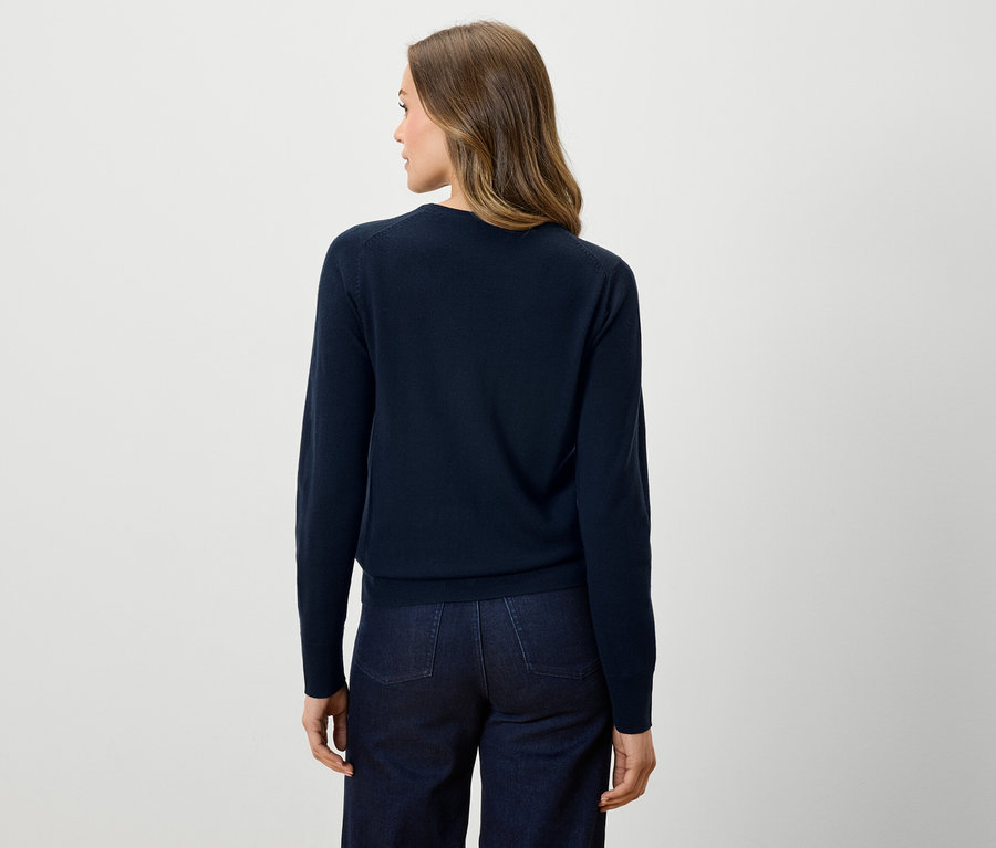 Hátulról látható egy nő sötétkék pulóverben és sötét farmerban.